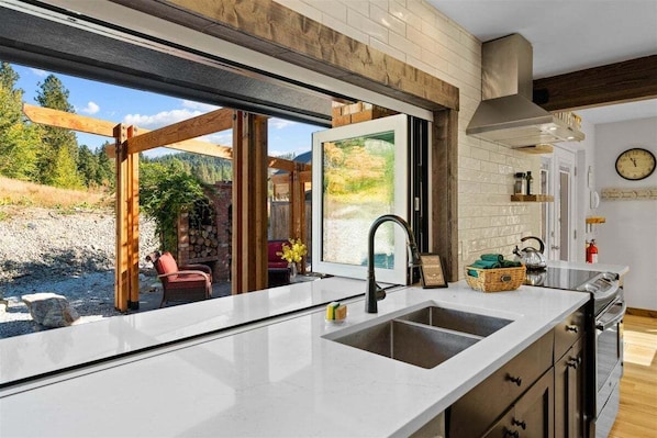 A kitchen with a large window, a sink, and a stove.