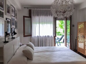 A bedroom with a bed, a desk with two lamps, a large window with curtains, and a view of the outdoors. - Comfortable, spacious, bright, and centrally located. Three double bedrooms (Venezia)