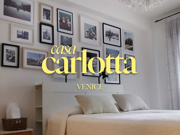 A hotel room with a bed, pillows, a bedside table, and a wall adorned with framed photographs. - Comfortable, spacious, bright, and centrally located. Three double bedrooms (Venezia)