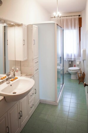 A bathroom with a white sink, mirror, cabinets, and a shower area. - Comfortable, spacious, bright, and centrally located. Three double bedrooms (Venezia)