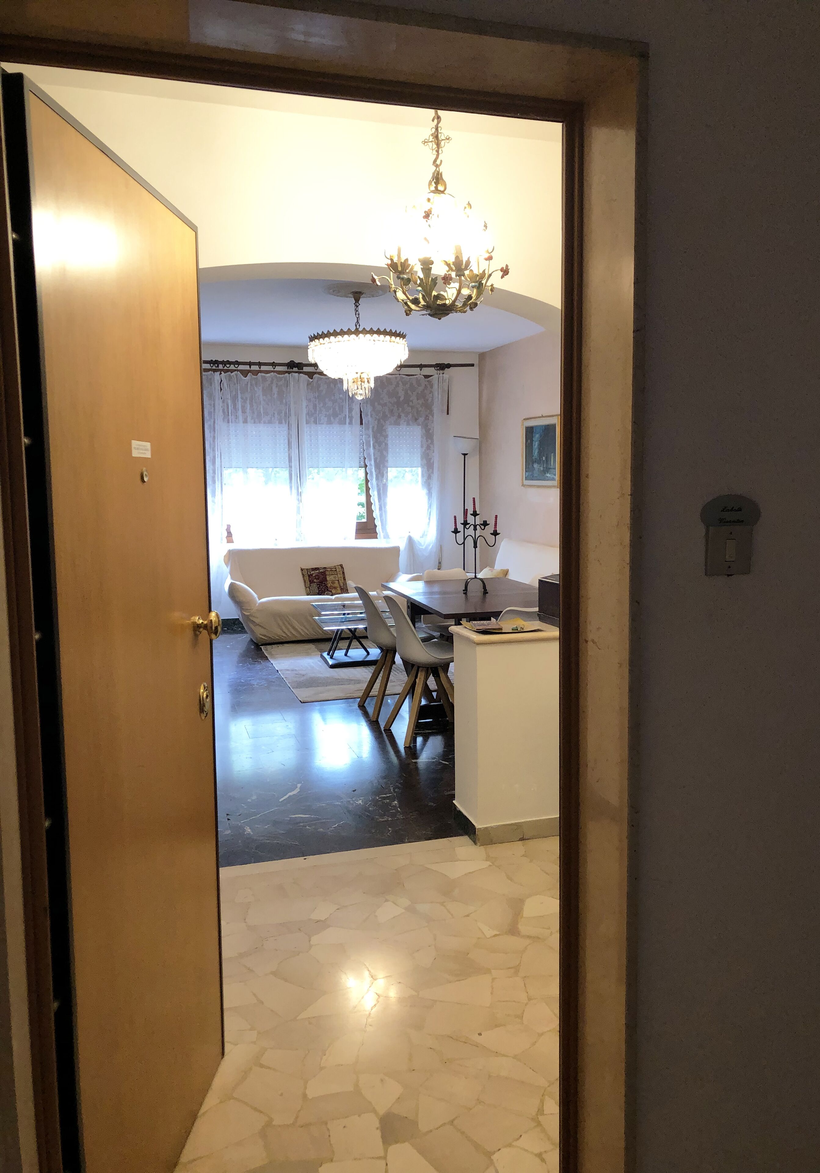 Una stanza con zona pranzo, un lampadario e pavimento piastrellato.