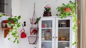 A small, well-organized balcony with a white cabinet, red chair, and various potted plants. - Cosy, spacious, bright and central. Three double bedrooms (Venezia)