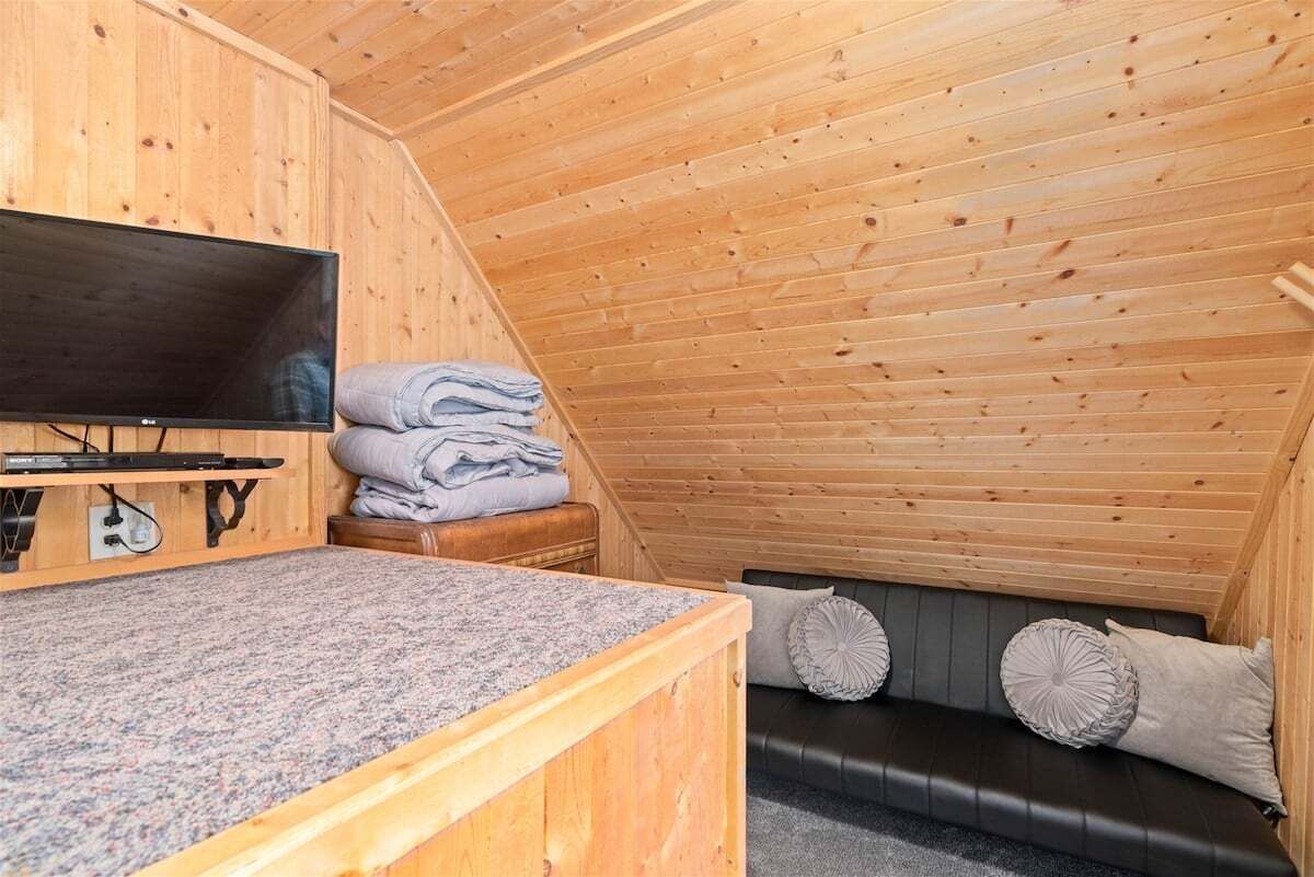 Ein Holzinterieur mit Fernseher, einer Granit-Arbeitsplatte, einem schwarzen Ledersofa und dekorativen Kissen sowie einem Stapel gefalteter Handtücher.