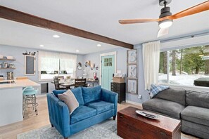 A living room with a blue sofa, a grey sofa, a wooden coffee table, and a ceiling fan.