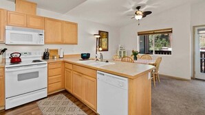 A kitchen with wooden cabinets, a microwave, stove, and dishwasher.