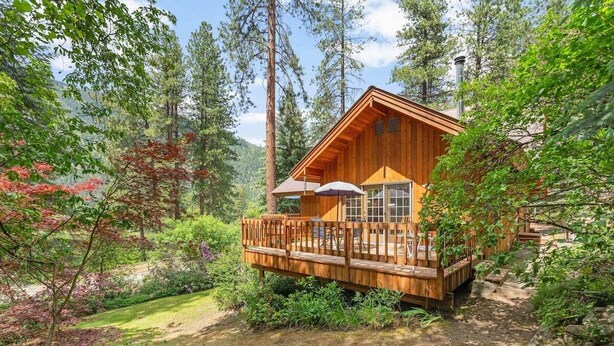 A cabin with a wooden deck, large windows, and a chimney. - Buddington Haus - Peaceful nature views (Leavenworth)