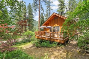 Une cabane dotée d’une terrasse en bois, de grandes fenêtres et d’une cheminée.