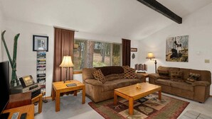 A living room with a sofa, coffee table, TV, and a bookshelf. - Woodsy Leavenworth Hideaway w/ Hot Tub + Fireplace, Near Trails (Leavenworth)