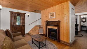 Un interior de madera con chimenea, un sofá, un comedor y una escalera.