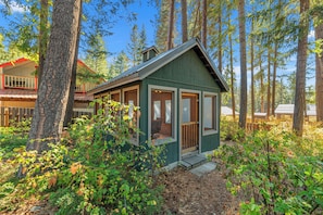 Une cabane dotée d’une véranda, entourée d’arbres.