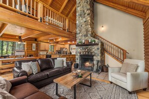 A spacious living room with a fireplace, leather sofas, a coffee table, and a stone accent wall.