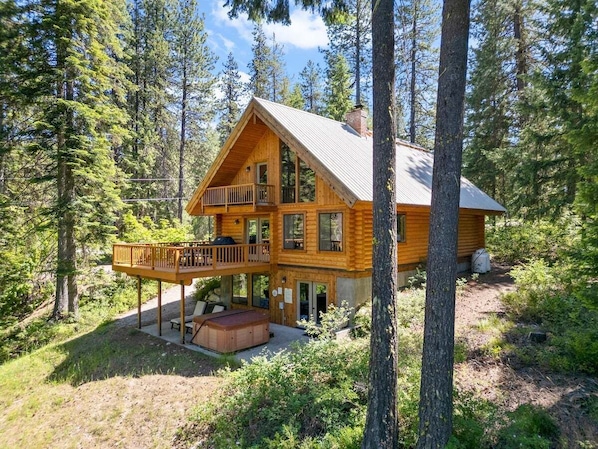 A log cabin with a balcony, a hot tub, and a deck.