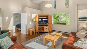 A spacious living area with a television, wooden furniture, and large windows. - Riverfront Hot Tub | 4BR Near Leavenworth (Leavenworth)
