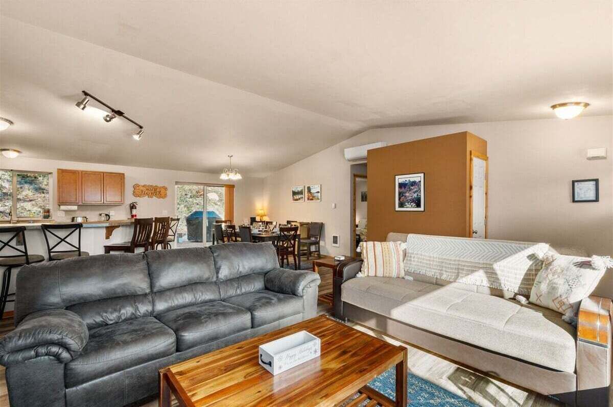 Sala de estar com sofá, mesa de centro e área de jantar ao fundo.