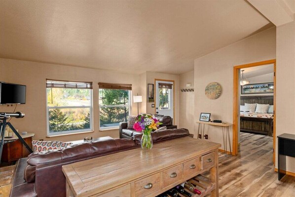 A living room with a wooden coffee table, leather sofa, and a TV.