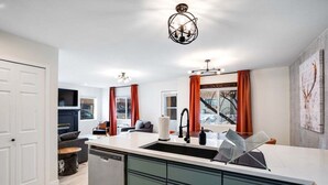 Una cocina moderna con una isla central, lavavajillas integrado y un amplio ventanal con cortinas.
