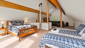 A bedroom with a wooden ceiling, a bed with a checkered bedspread, a desk, and a chair. - Pet-Friendly Lake Wenatchee Cabin + Deck (Leavenworth)
