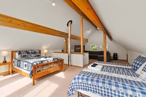 Un dormitorio con techo de madera, una cama con colcha escocesa, un escritorio y una silla.
