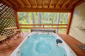 A hot tub on a wooden deck with a view of trees and a sign indicating quiet time. - Riverfront Family Retreat Near Lake Wenatchee (Leavenworth)