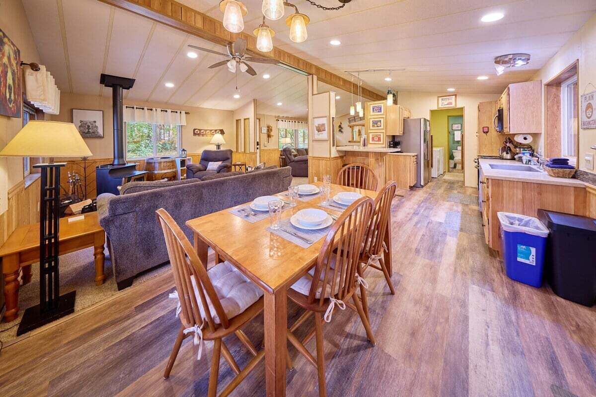 Un intérieur chaleureux, aménagé dans le style d’un chalet, avec un coin repas, des meubles en bois et une petite cuisine.