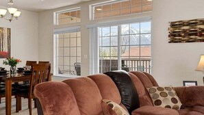 Ein geräumiges Wohnzimmer mit großem Fenster, Essbereich und einer modernen Pendelleuchte.