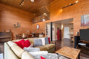 A wooden interior with a sofa, coffee table, and a dining area.