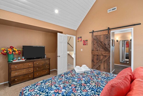 Un dormitorio con cama, cómoda, televisor y una puerta corredera estilo granero.