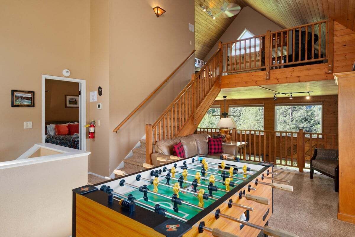 Ein gemütliches Zimmer mit einem Kicker, einer Treppe und einem Balkon.
