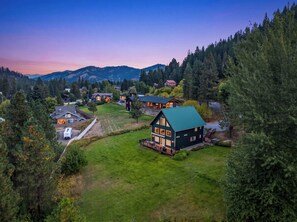 A residential area with houses, a green lawn, and a mountain backdrop.