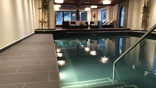 An indoor swimming pool with a tiled floor and a clear water surface.