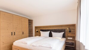 A bedroom with a wooden bed frame, a large wardrobe, and a nightstand with a lamp.