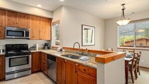 Una cocina moderna con armarios de madera, microondas integrado, estufa y lavavajillas.