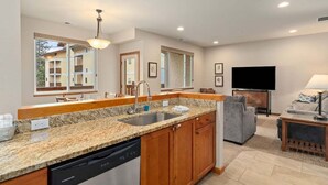 Una cocina moderna con encimeras de granito, lavavajillas y armarios de madera.