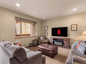A living room with a flat-screen TV, a fireplace, and a large window. - Pet-friendly, Two-Level Condo Downtown (Leavenworth)