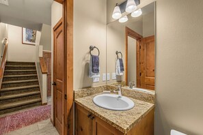 A bathroom with a granite countertop, a white sink, and a mirror above it. - Pet-friendly, Two-Level Condo Downtown (Leavenworth)