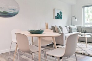 A modern living room with a round table, two chairs, a sofa, and a coffee table.