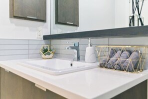 A bathroom with a white sink, a gold-rimmed towel rack, and a hexagonal mirror cabinet.