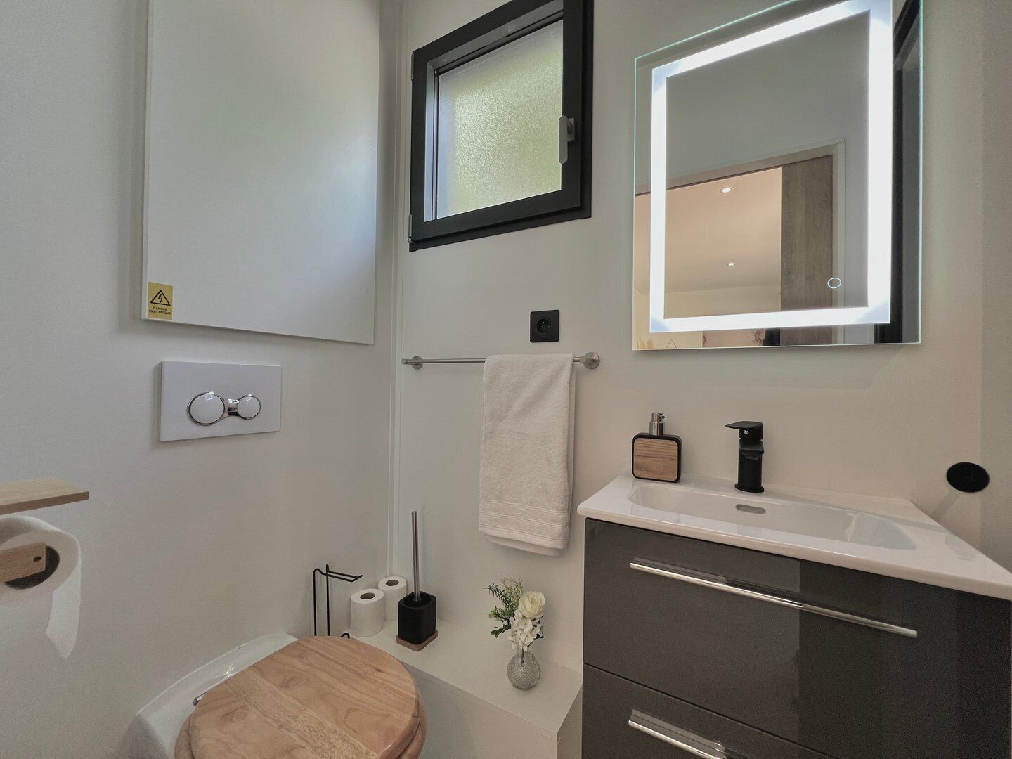 Un baño moderno con inodoro, lavamanos, espejo y toallero.