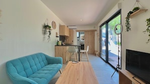 Un salon moderne avec un canapé bleu, une table basse en bois et un téléviseur posé sur un meuble en bois.