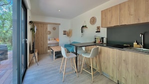 Une cuisine moderne avec des meubles en bois, un plan de travail noir et un coin repas comprenant une table et des chaises.