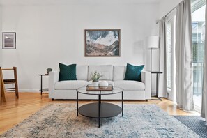 Una sala de estar con un sofá, una mesa de centro y un cuadro en la pared.