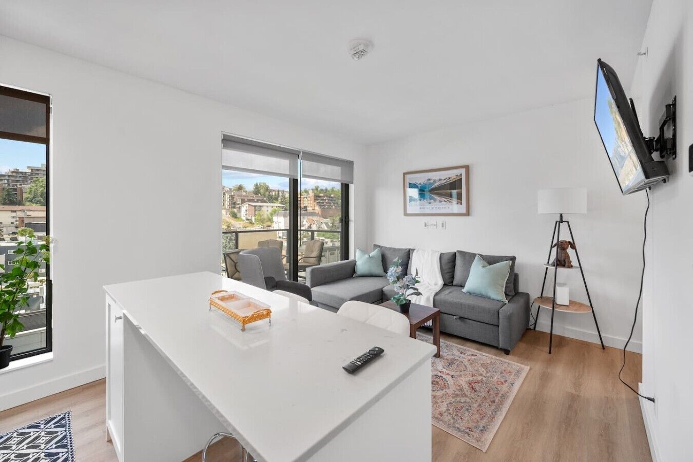 Una sala de estar moderna con una mesa blanca, un sofá gris y un televisor montado en la pared.
