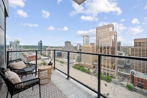 A balcony with a view of a cityscape, including high-rise buildings and a clear sky.