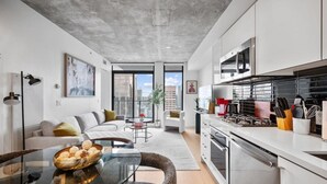 A modern apartment with a kitchen, dining area, and living room. - DT Views |UG Park | Mins to Saddledome | Gym (Calgary)