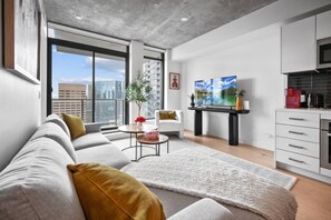 A modern apartment with a living room, dining area, and kitchenette.
