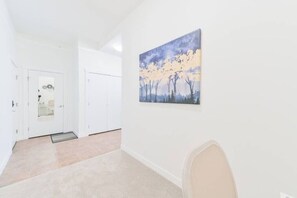 Um corredor com uma porta, um quadro e um tapete.