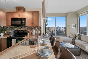 Cozinha moderna com uma ilha grande, eletrodomésticos de aço inoxidável e vista para uma ponte.