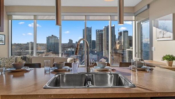Une cuisine moderne dotée d’un grand îlot central, d’appareils électroménagers en acier inoxydable et offrant une vue sur la ville.