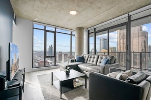 Uma sala de estar moderna com um sofá grande, uma mesa de centro e uma televisão.