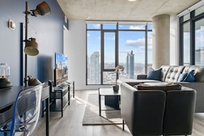 Uma sala de estar moderna com vista para a cidade, um sofá, uma mesa de centro e uma televisão.